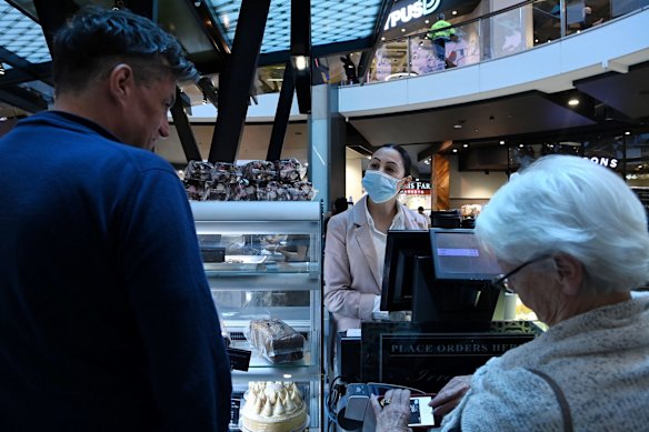Pattison's franchisee Sera Ozbey, centre, serves customers in Westfield Bondi Junction shopping centre on the first day of relaxed COVID-19 restrictions for fully vaccinated people. 