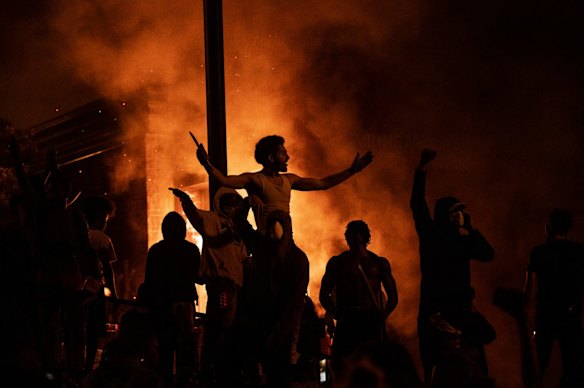 Protesters cheer as the Third Police Precinct burns behind them on May 28, 2020 in Minneapolis, Minnesota. Unrest continued after the death of George Floyd and police abandoned the precinct building, allowing protesters to set fire to it.