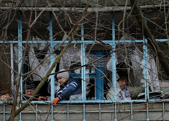 Residents clean up their damaged apartment after missiles landed nearby.
