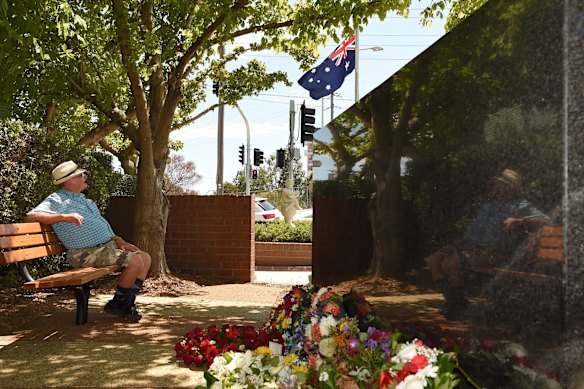 A man looks at the Australian flag at half mast near the wreaths at the monument in Granville to mark the 40th anniversary of the Granville Train Disaster.