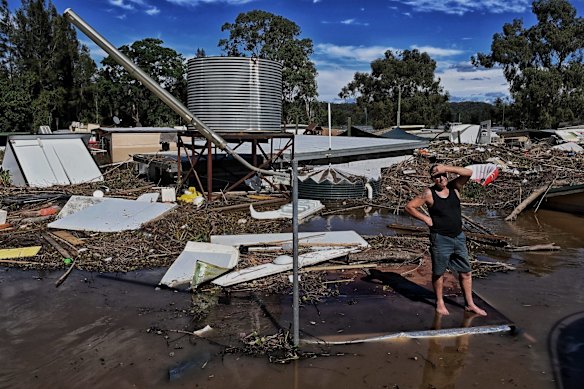 A resident of the St Georges Caravan park along the Hawkesbury River stands on a building as the remains of his home and many others are slowly swept away. 25 March, 2021.

