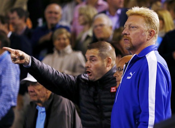 A man gestures next to Djokovic's coach Boris Becker.