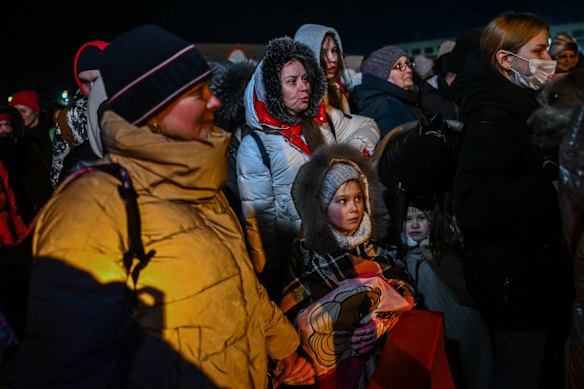 People who fled the war in Ukraine wait in line to board a bus as police officers and Polish territorial defense soldiers help to manage the crowd after crossing the Polish-Ukrainian border in Medyka, Poland.