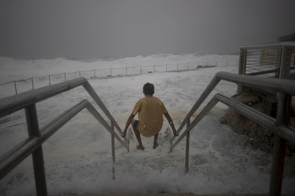 Wild weather at Bronte as a swimmer tries to enter the ocean pool.