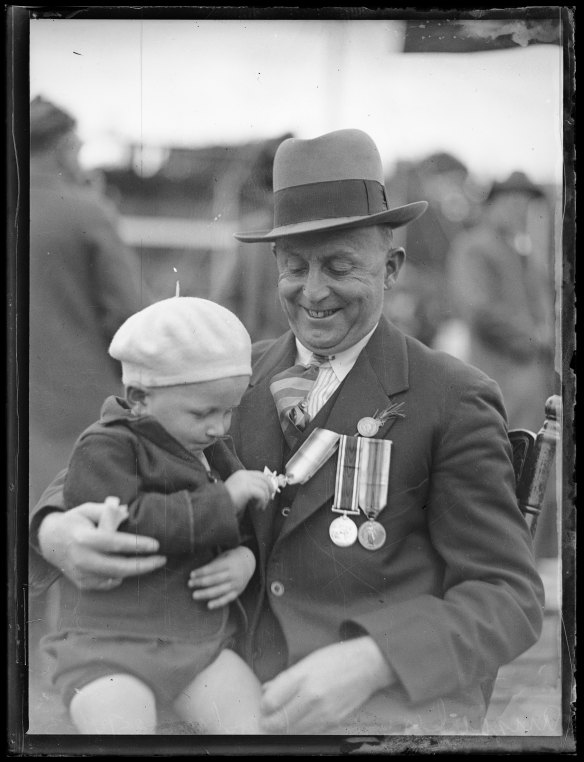 Child playing with the medals of a returned soldier at an Anzac Day service in Petersham in 1933. Image courtesy of the National Library of Australia.