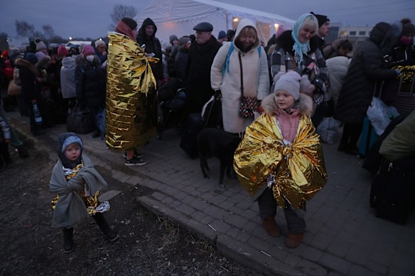 Margarita, 5, and her brother Kiril, 4, arrive with their mother and grandmother along with others from war-torn Ukraine on a freezing evening at the Medyka border crossing into Poland.