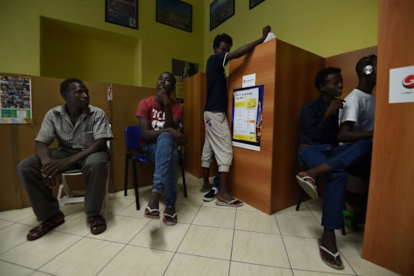Idris Ahmed 25 (left) and Adam Abkar Mohamed 20 (2nd from left) from Darfur in Sudan wait to use the phones and computers check to see if their money has been wired to the western union outlet in Milan so that they can proceed to another country.
