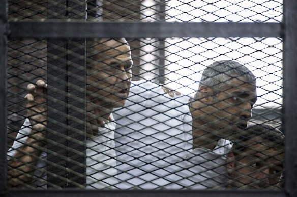 Al-Jazeera news channel's Australian journalist Peter Greste (L) and his colleagues, Egyptian-Canadian Mohamed Fadel Fahmy (C) and Egyptian Baher Mohamed , listen to the verdict inside the defendants cage during their trial for allegedly supporting the Muslim Brotherhood on June 23, 2014