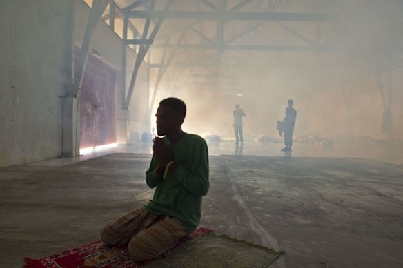 TOPSHOTS
A rescued Bangladeshi migrant (C) prays at a corner while Indonesian personnel fumigate a warehouse converted into sleeping quarters for migrants at a fishing port in Langsa in Aceh province on May 19, 2015. The migrants mostly Rohingyas from Myanmar and Bangladesh were rescued by Indonesian fishermen off Langsa on May 15. The Philippines said May 19 it was ready to help Rohingya and Bangladeshi boatpeople, as its Southeast Asian neighbours faced outrage for turning them away. 