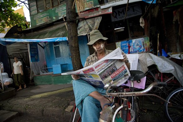 A rickshaw rider reads a newspaper as he waits for passengers in Yangon, Myanmar.