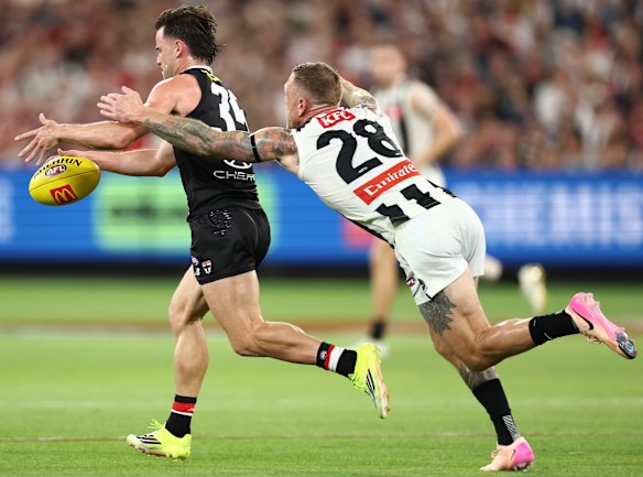 Jack Sinclair of the Saints kicks the ball with Tim Membrey in chase.