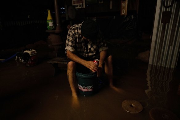 An exhausted friend takes a break from bailing as the waters continue to rise, as friends and family of Dick Sharkey attempt to protect his home from flooding, Friday November 4, 2022.