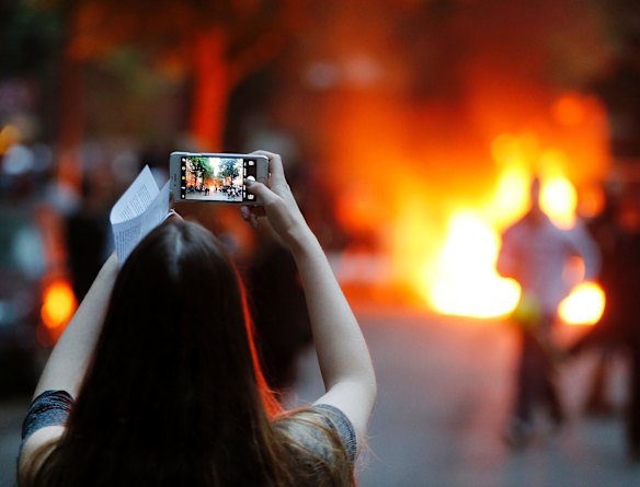 A young woman takes a picture of a burning barricade during a protest against the G-20 summit in Hamburg, northern Germany.
