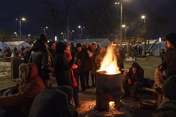 People keep warm by fires outside the main rail terminal in Lviv, Ukraine. Ukrainians from the eastern and central parts of the country have increasingly fled to cities in the country's west that have so far been considered safer.