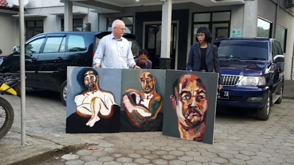 Australian lawyer Julian McMahon with three self-portraits by Sukumaran: <i>The 72 hours just started</i>, <i>Strange Day</i> and <i>Our new prints: A bad sleep last night</i>.
