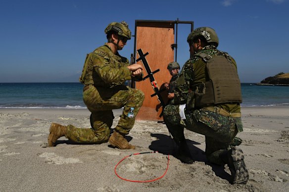 Sapper Nicholas Field (left) with the 2nd Combat Engineer Regiment instructs how to set a charge on a makeshift door to two marines.