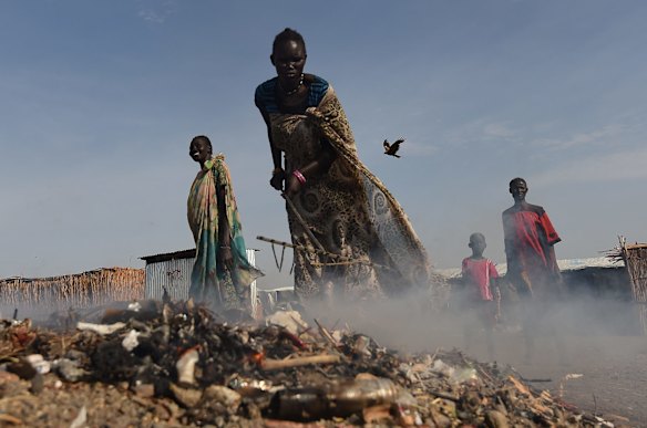 A woman tends a fire of burning rubbish inside the UNMISS Bentiu Protection of Civilians site over 100,000 people are forced to live in having fled the violence. 