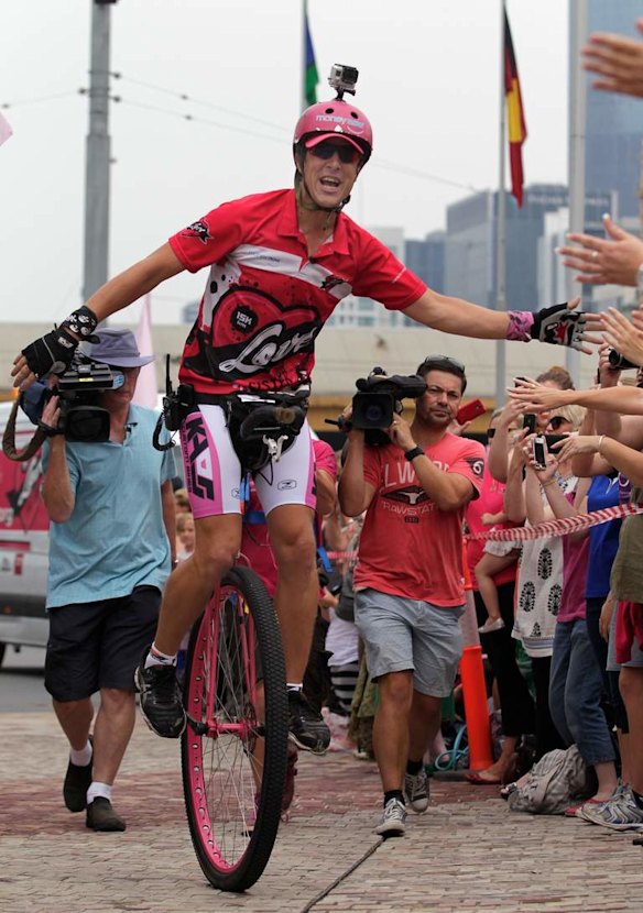 Samuel Johnson celebrates  crossing the finish line after his year-long Love Your Sister unicycle trek.