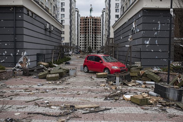 An abandoned car sits outside a damaged apartment building in the town of Bucha. 