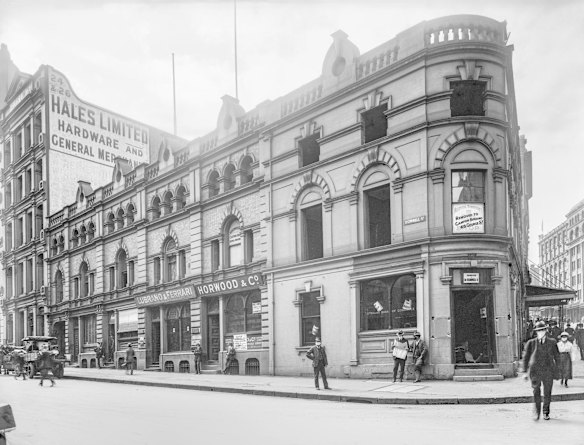 Hunter and O'Connell streets, 1919. When this corner building was captured by the camera on 19 February 1919, Sydney was in the midst of an outbreak of the deadly Spanish influenza pandemic. The requirement to wear a mask in public was enforced by police. Not all obeyed this command. The two young men outside Horwood & Co have slipped their masks off. The windows of Lubrano & Ferrari are marked with crosses.