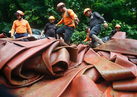 Rescue personnel arrange large hoses and additional water pumps to continue a search operation for a young soccer team and their coach in a large flooded cave.