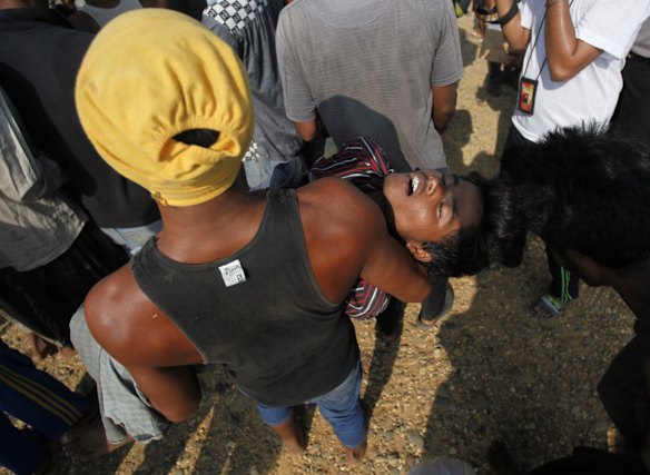 An unconscious migrant is carried by a friend upon arrival in Simpang Tiga, Aceh province, Indonesia, Wednesday, May 20, 2015. Hundreds of migrants stranded at sea for months were rescued and taken to Indonesia, officials said Wednesday, the latest in a stream of Rohingya and Bangladeshi migrants to reach shore in a growing crisis confronting Southeast Asia. 