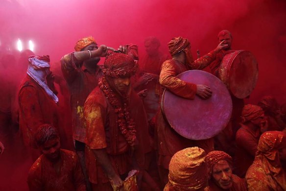 Members of a band stand in a cloud of coloured powder inside a temple at the village of Barsana, India.