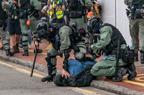 A pro-democracy supporter is detained by riot police during an anti-government rally.