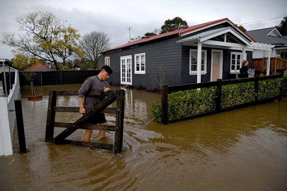 Camden residents Jai And Belinda Prestwidge evacuate, taking front gates that weren't attached properly and at risk of being washed away.