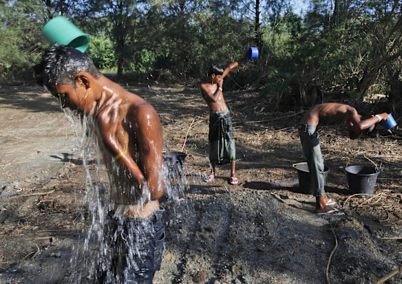 Rohingya youths use buckets to take shower outside a temporary shelter in Langsa, Aceh province, Indonesia, Tuesday, May 19, 2015. Indonesia has sheltered more than 1,000 Rohingya and Bangladeshi migrants who washed onto Aceh and North Sumatra provinces last week. 