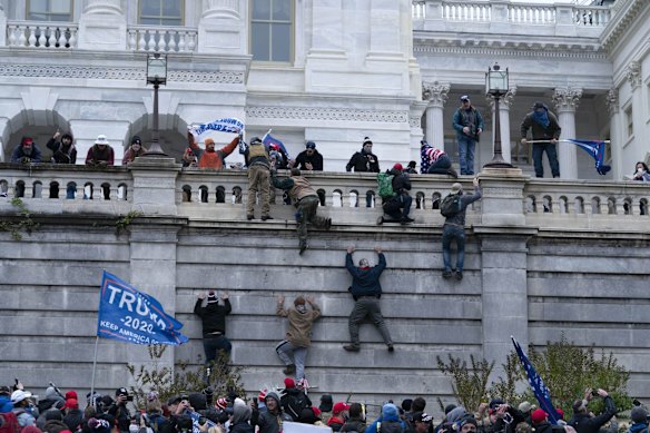 Supporters of President Donald Trump climb the west wall of the the US Capitol.