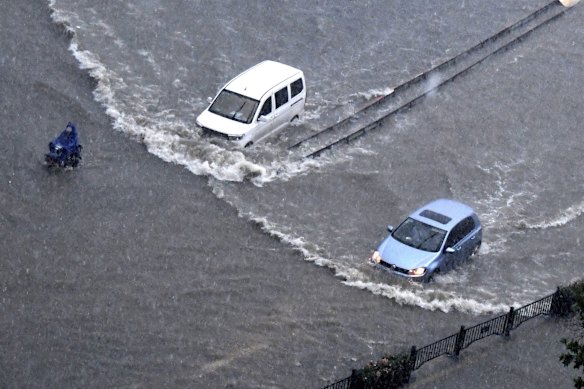 Vehicles pass through floodwaters in Zhengzhou in central China's Henan Province on Tuesday. At least a dozen people died in severe flooding that trapped people in subways and schools, washed away vehicles and stranded people in their workplaces overnight.
