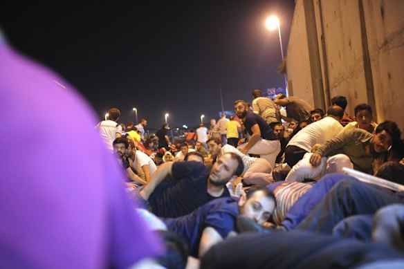 People protesting against the coup, try to protect themselves during a firefight between police and army forces in Istanbul.