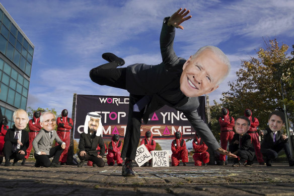 Climate campaigners wearing masks of world leaders including US President Joe Biden.