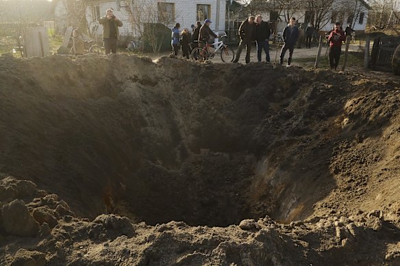 Resident look into a massive bomb crater in the village of Horodnya in the Chernihiv region. 