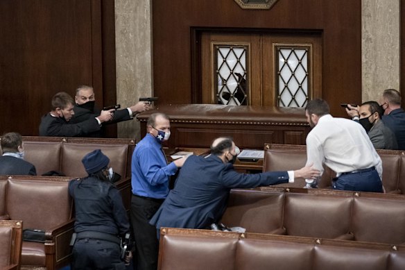 Security forces draw their guns as rioters loyal to President Donald Trump try to break into the House of Representatives chamber to disrupt the Electoral College process at the Capitol in Washington. January 6, 2021.