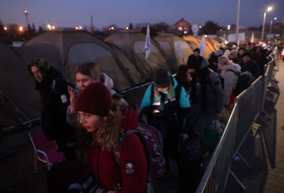 People who have just crossed from war-torn Ukraine into Poland wait to board buses provided by Polish authorities at the Medyka border crossing in Medyka, Poland. 