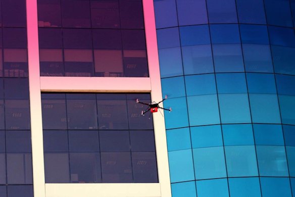 A drone buzzes the side of a building.