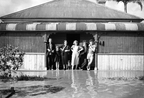 A family stands at the doorway of the doorway of its flooded home in Maitland, NSW, 8 August 1952.