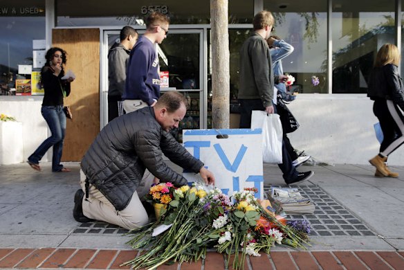 Stephen Nichols arranges flowers left in front of IV Deli Mart, where part of Friday night's mass shooting took place by a drive-by shooter.