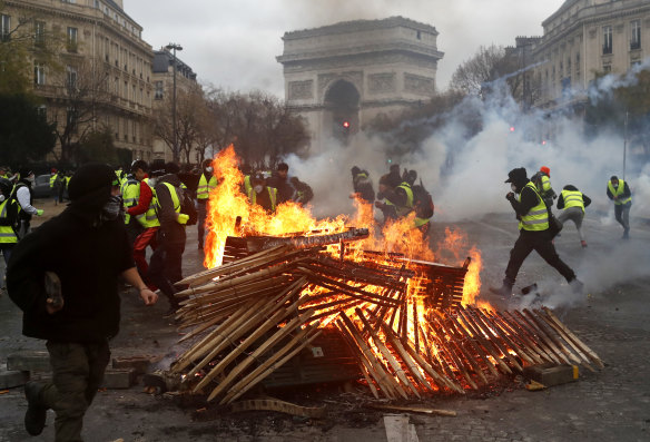 Demonstrators run by a burning fire near the Arc de Triomphe.