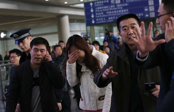 A relative (C, in white) of a passenger onboard Malaysia Airlines flight MH370, covers her face as she cries at the Beijing Capital International Airport in Beijing.