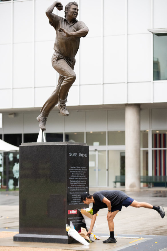 A fan leaves flowers at Shane Warne’s statue at the MCG on Saturday.
