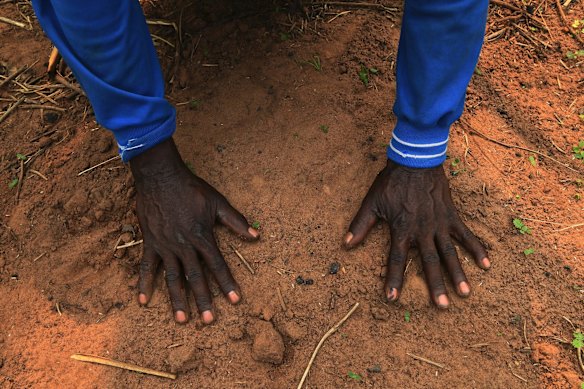 Mpeta Tshipalela lays his hands on the mass grave where his fifteen year old grandson Kapena Muanza is buried with several other civilians killed when their village Kamuandu in Kasai Central was attacked. Their bodies were dumped in the village well which the community has filled in. Those who survived the attack fled to the bush where some lived for up to a year.