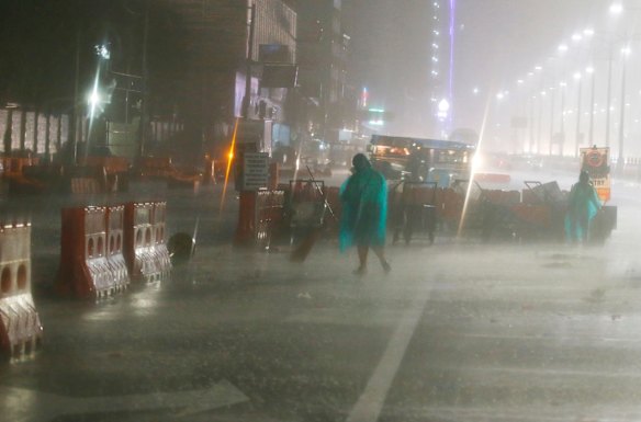 Street sweepers go about their daily business amidst the rain and strong winds brought about by Typhoon Mangkhut.