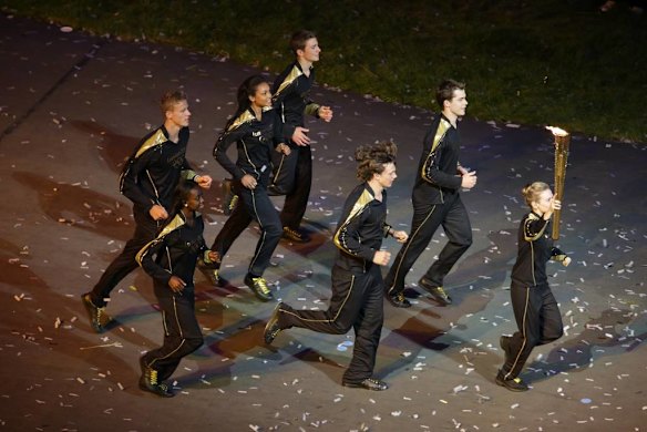 A group of young athletes run into the stadium carrying the Olympic flame. They then lit the cauldron.