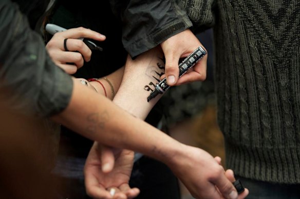 Writing the phone number for a legal service on their arms, protesters prepare for arrests.