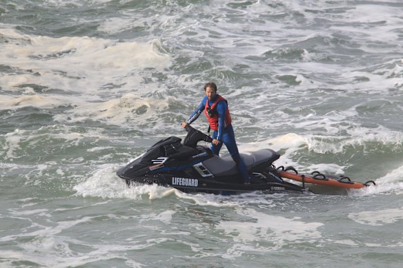 A Bondi lifeguard searches for a missing swimmer in rough water off Bondi Beach.
