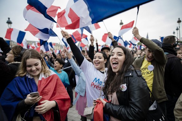Supporters of Emmanuel Macron, French presidential candidate, not pictured, wave French flags while reacting as vote projections are announced in the second round of the French presidential election in Paris, France, on Sunday.