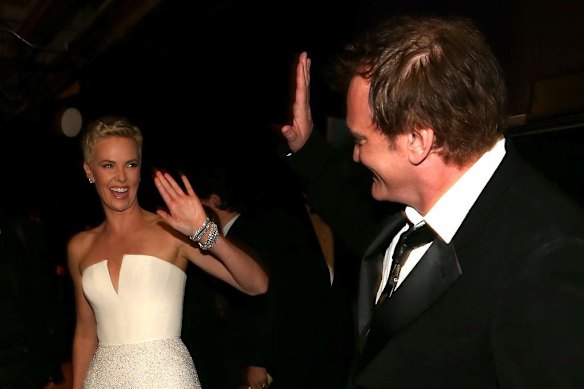 Actress Charlize Theron (L) and writer/director Quentin Tarantino, winner of the award for Original Screenplay for Django Unchained, high five eachother backstage during the Oscars.